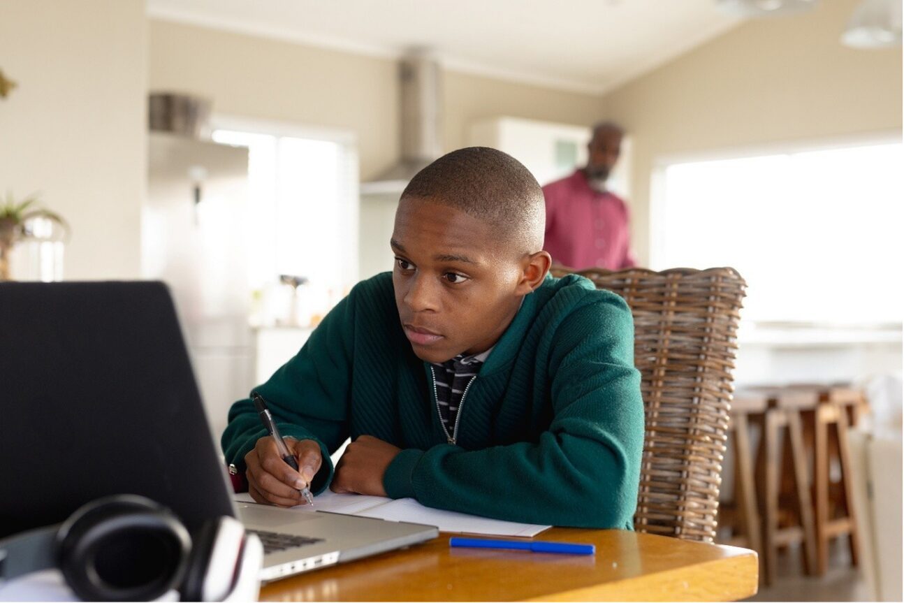 Teen homeschool candidate registering for the October/November exam series online with books and laptop